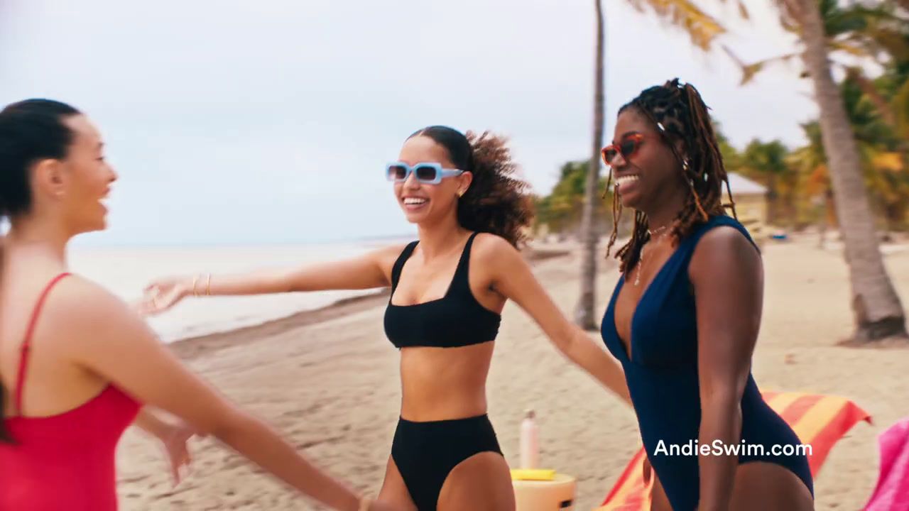 a group of women standing next to each other on a beach