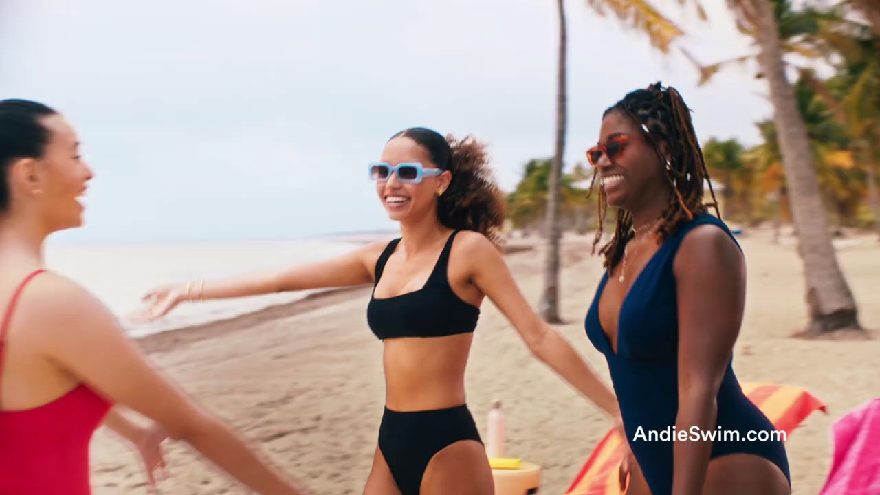 a group of women standing next to each other on a beach