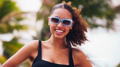 a woman wearing sunglasses and smiling for the camera