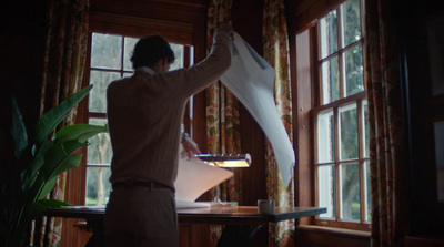 a man standing in front of a window holding a piece of paper