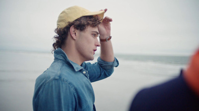 a young man wearing a yellow hat on the beach