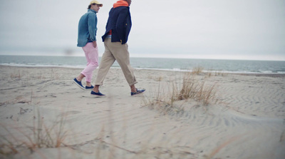 two people walking on a beach near the ocean