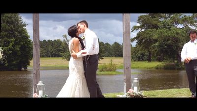 a bride and groom kissing in front of a lake