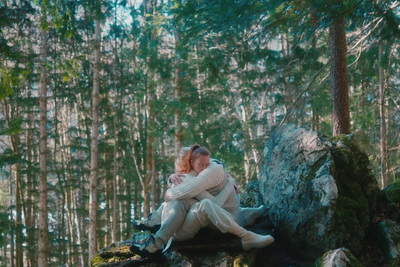 a woman sitting on a rock in the woods