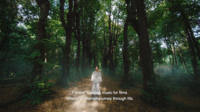 a woman in a white dress walking through a forest