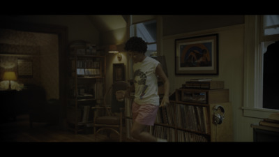 a man standing in a living room next to a book shelf