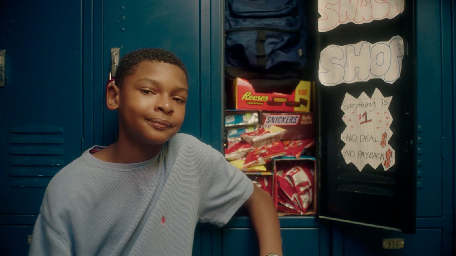 a young boy standing in front of a blue locker