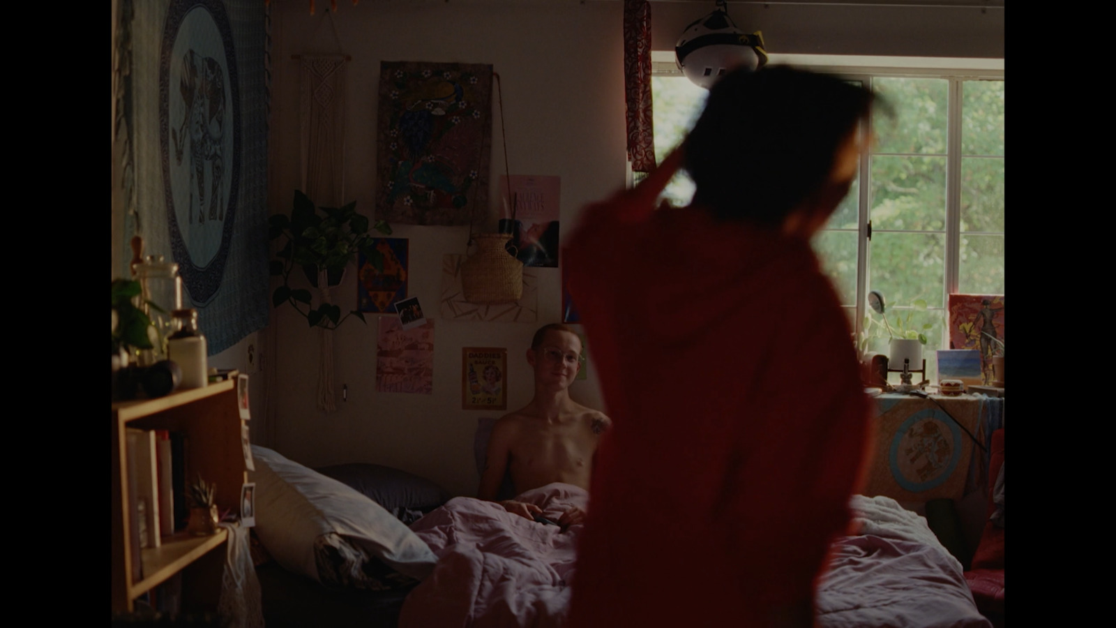 a woman in a red robe standing in a bedroom