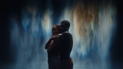 a man and a woman standing in front of a waterfall