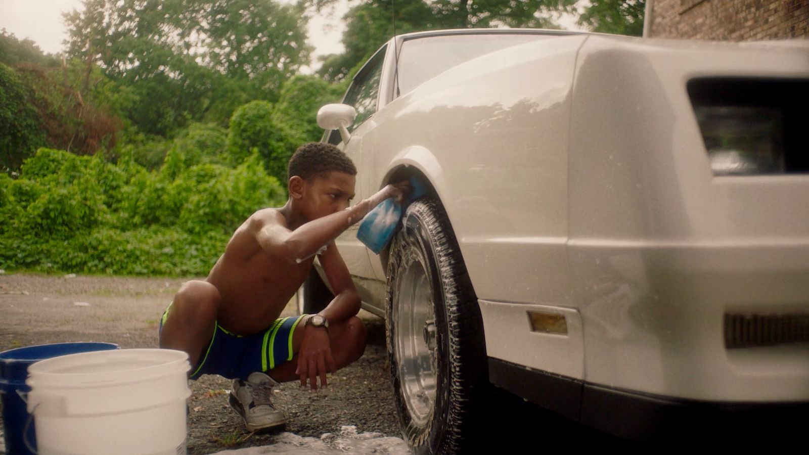 a young boy is washing his car tire