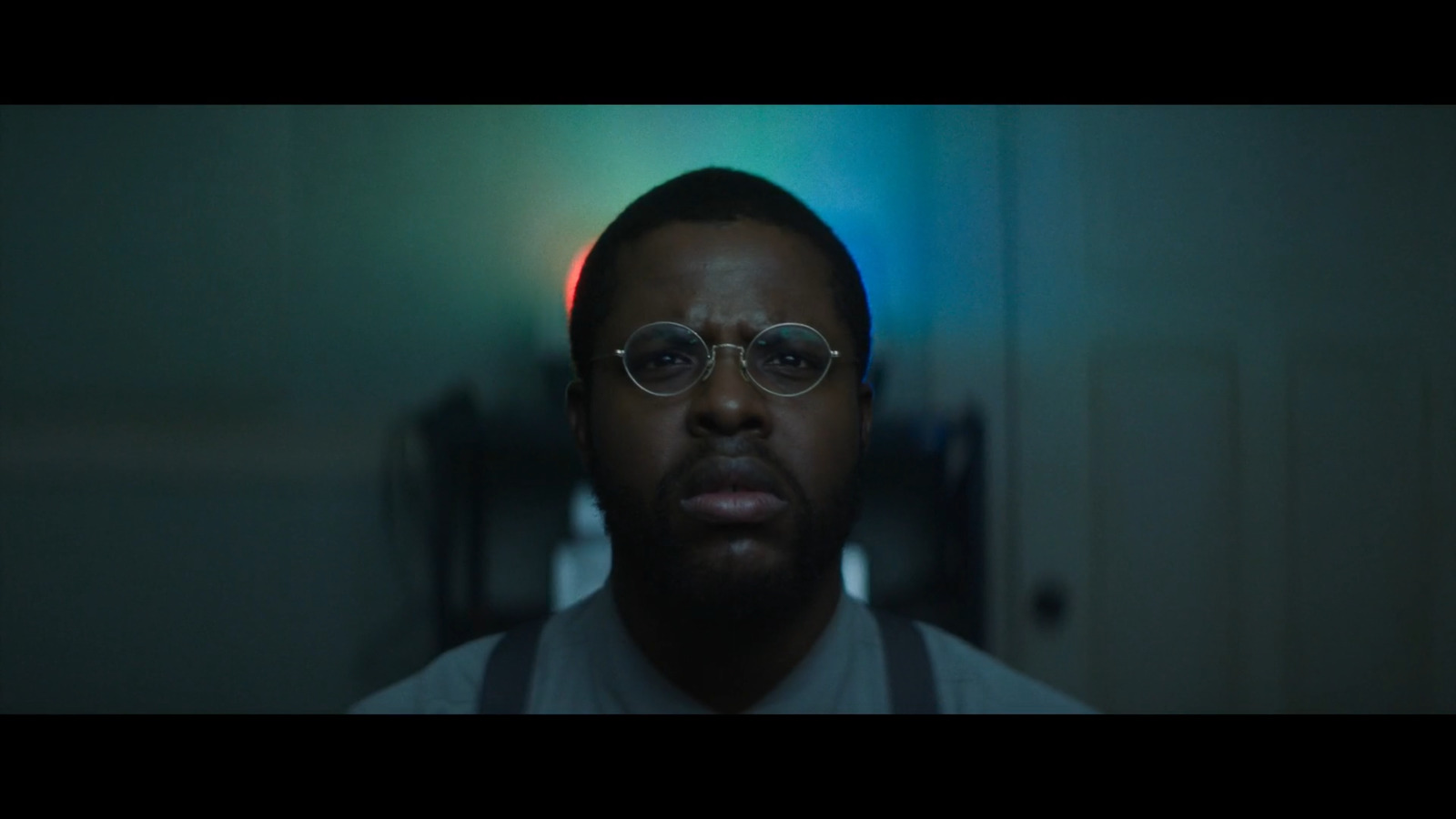 a man wearing glasses in a dark room