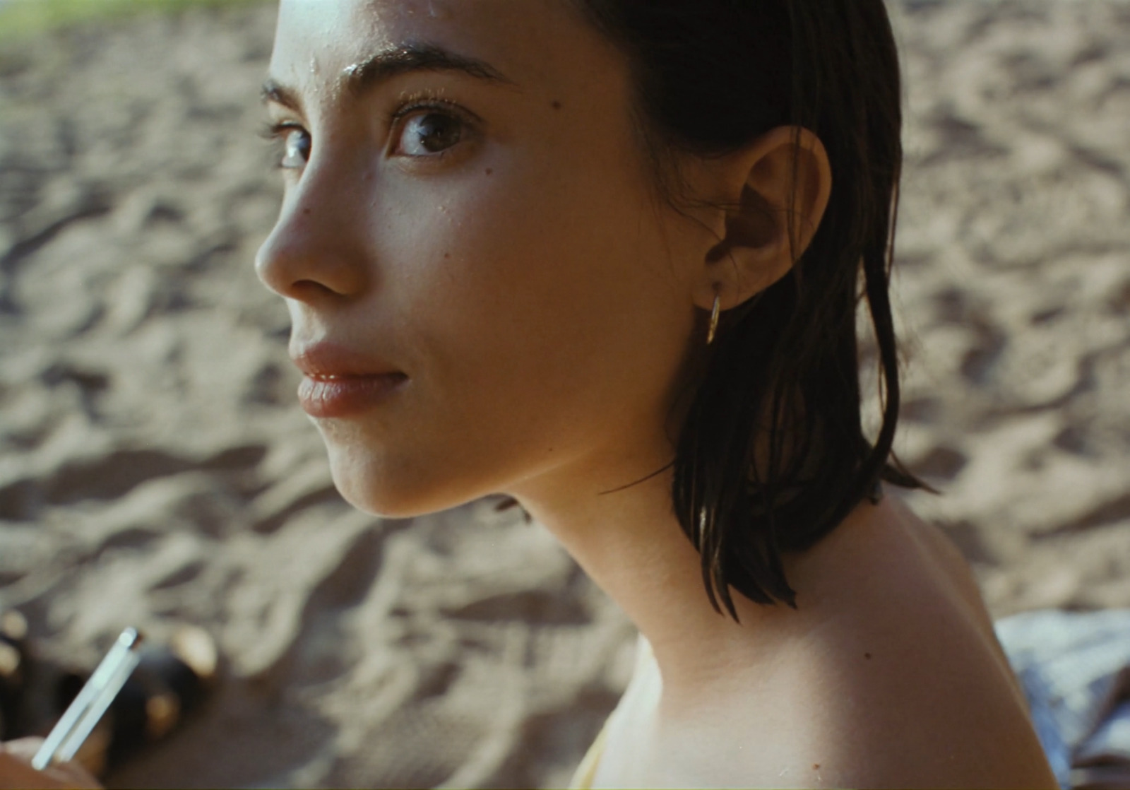 a woman is sitting in the sand with a pen in her hand