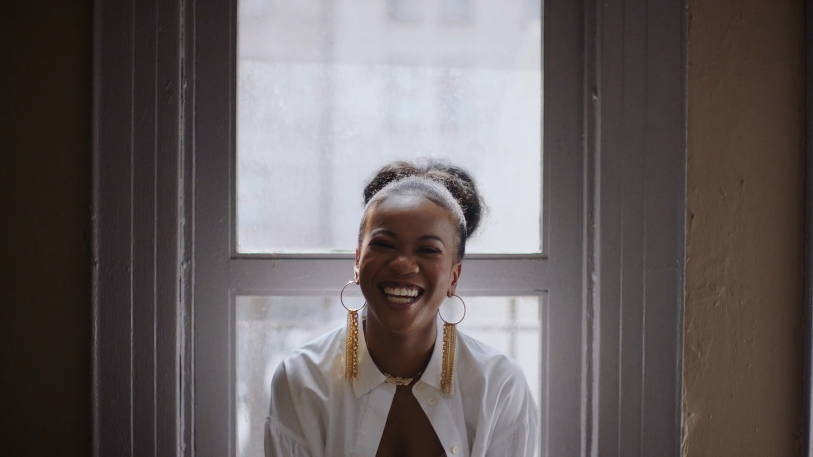 a smiling woman sitting in front of a window