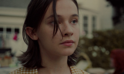 a close up of a person with a house in the background