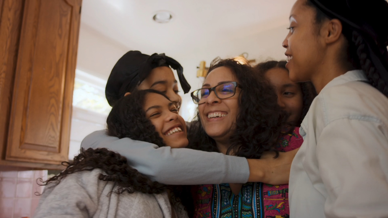 a group of women hugging each other in a kitchen