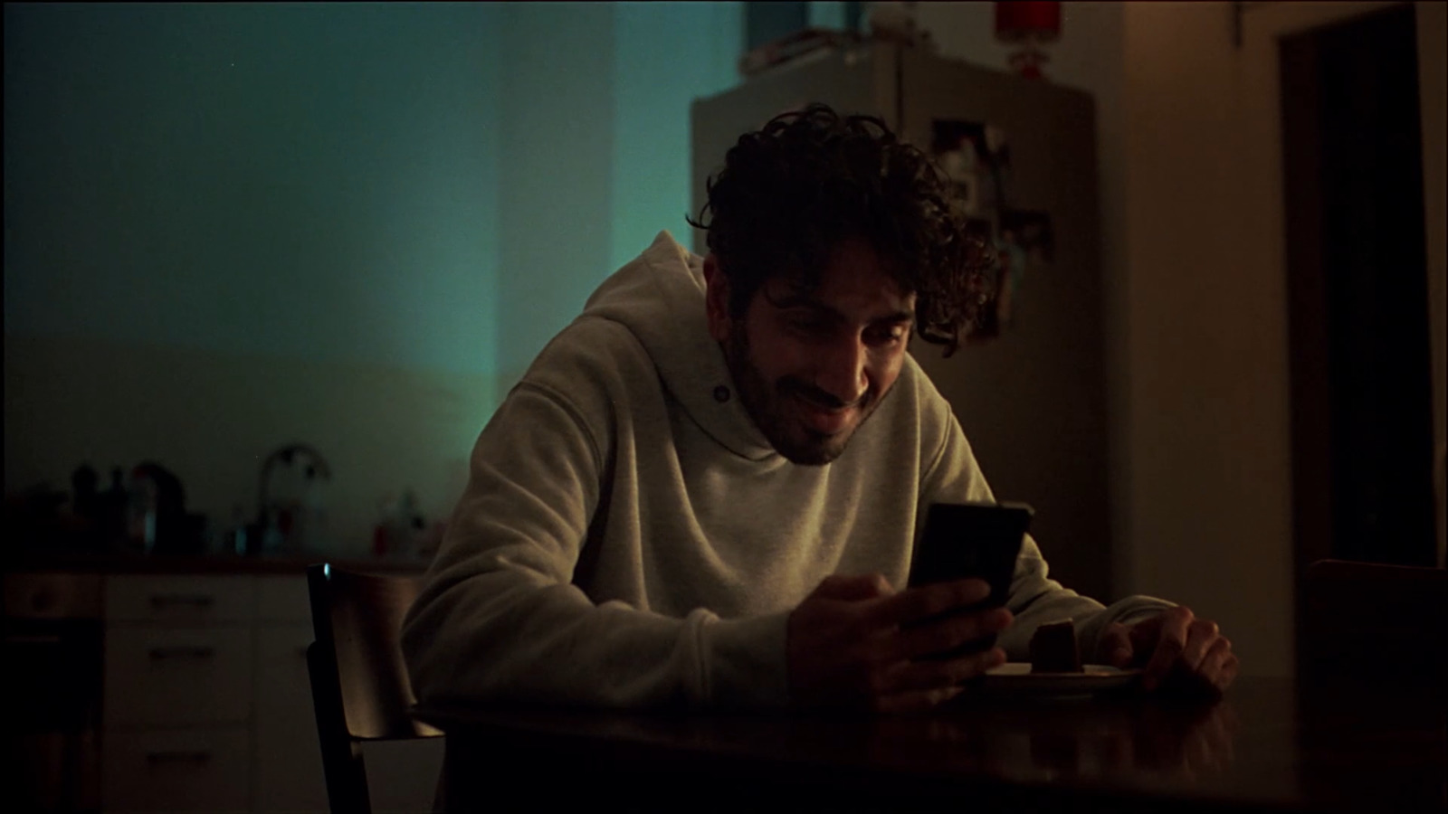 a man sitting at a table looking at a cell phone