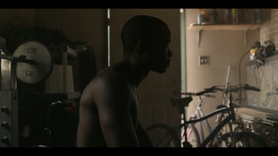 a shirtless man standing in a kitchen next to a bicycle