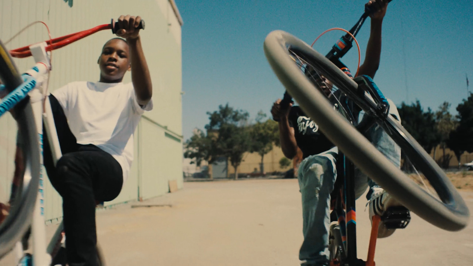 a young man riding a bike next to another young man