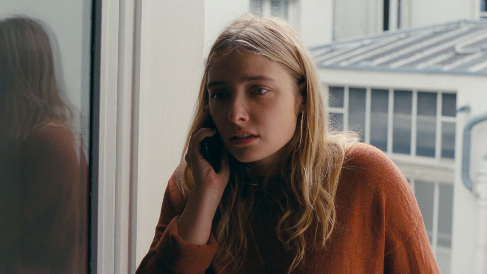 a woman talking on a cell phone next to a window