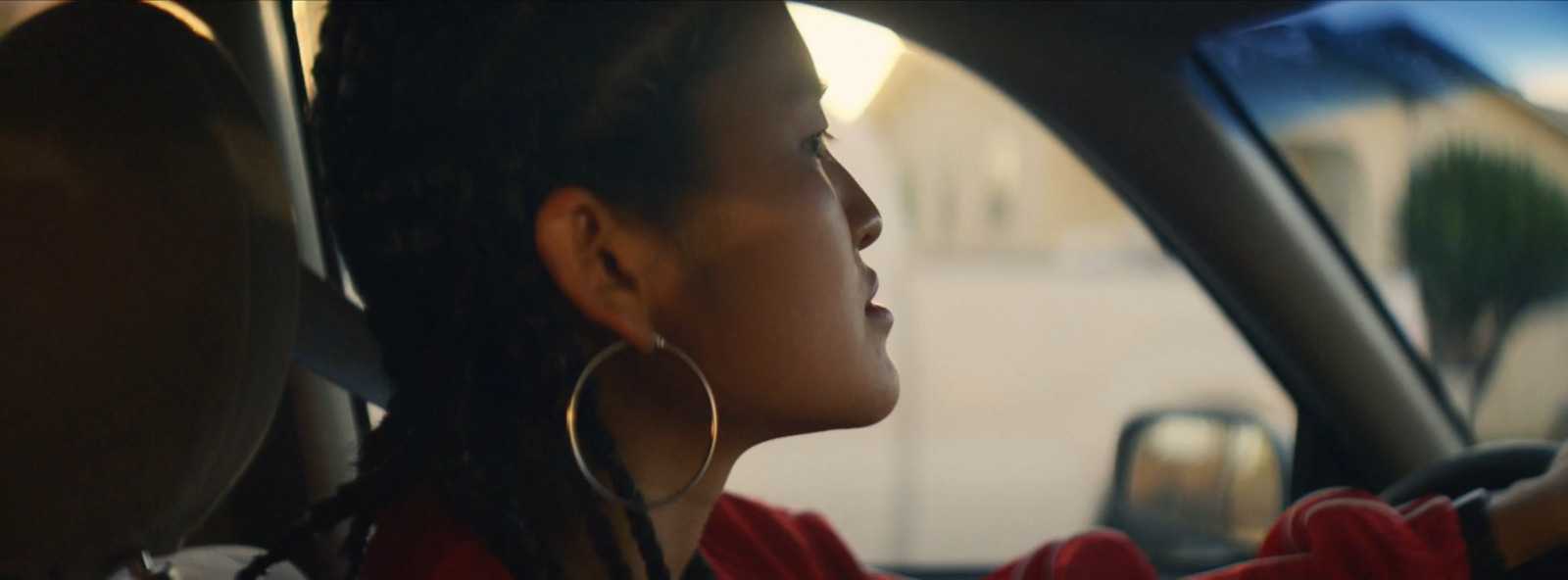 a woman sitting in a car with her hand on the steering wheel