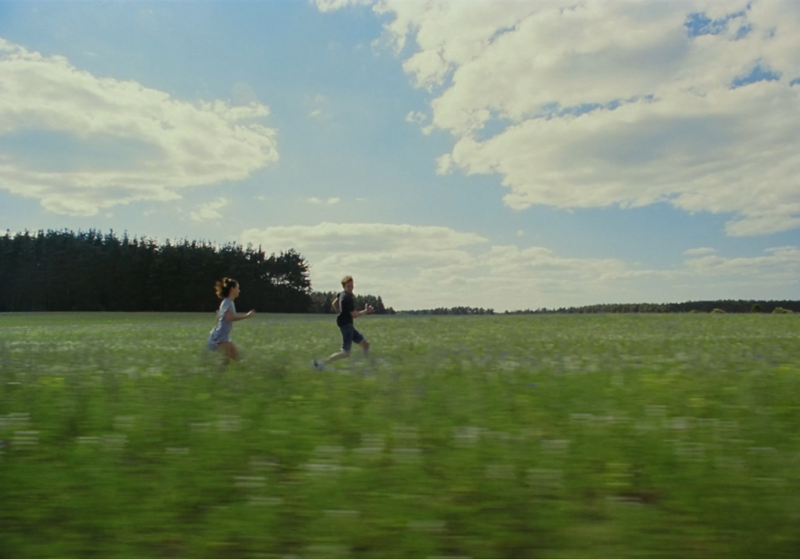 a couple of people walking across a lush green field