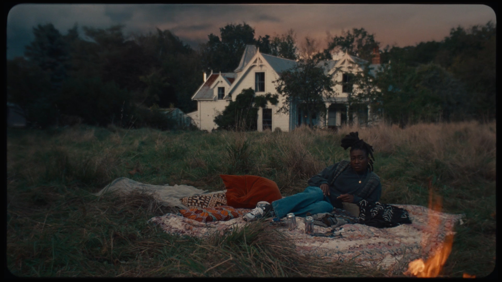 a woman sitting on a blanket next to a fire