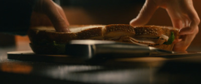 a person cutting a sandwich on a cutting board