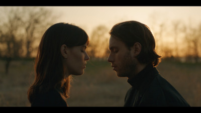 a man and a woman facing each other in a field