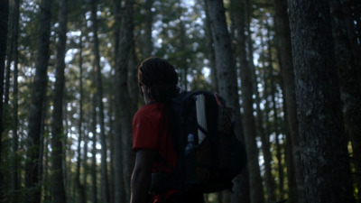 a man with a backpack walking through a forest