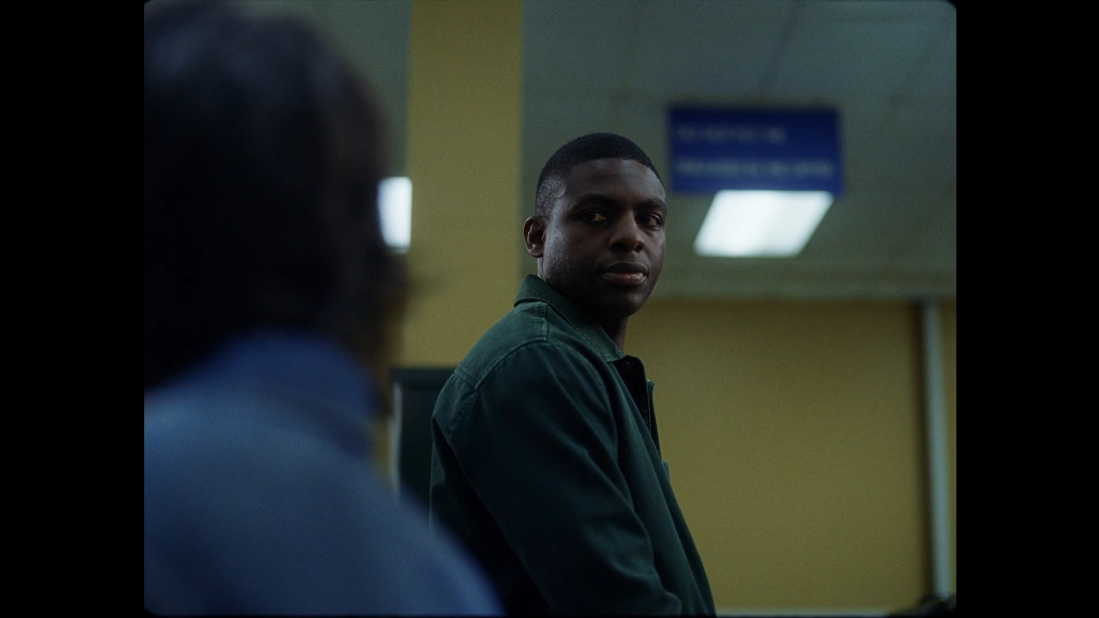 a man in a green shirt standing in a room