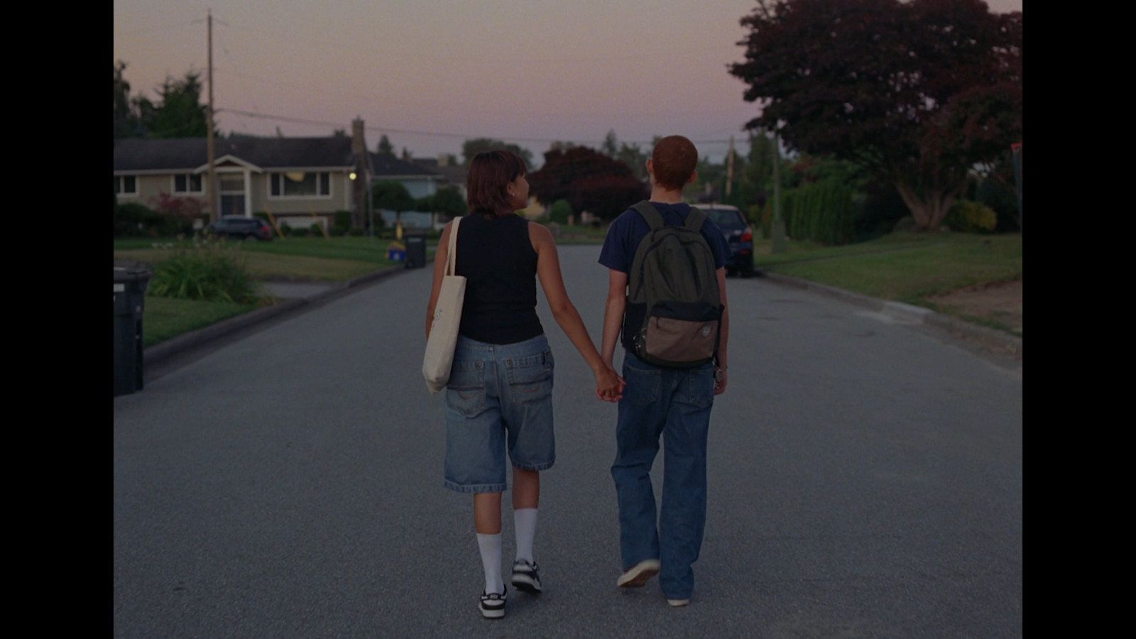 two people walking down a street holding hands