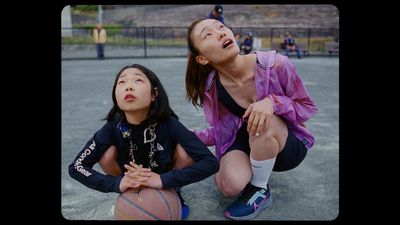 a woman kneeling down next to a little girl holding a basketball