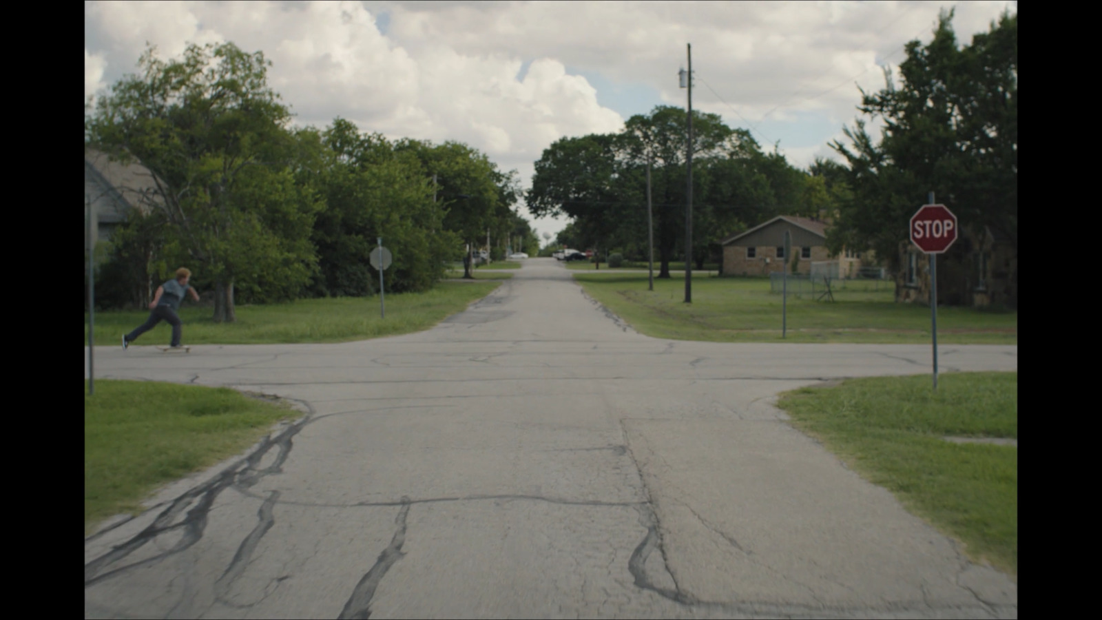 a man riding a skateboard down a street next to a stop sign