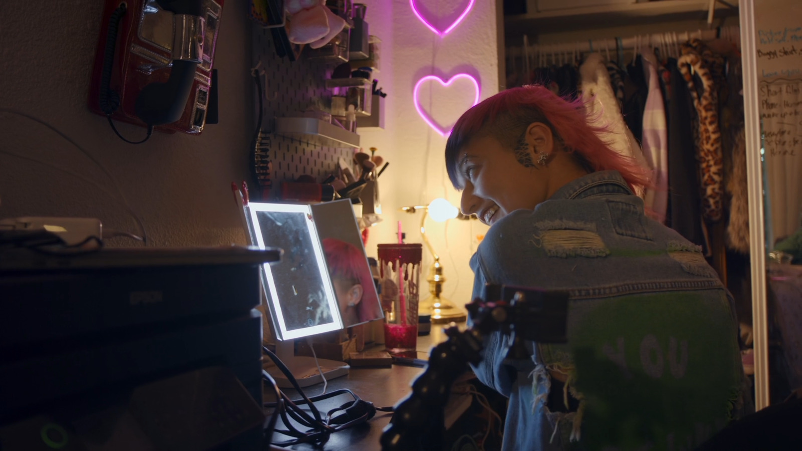 a woman with pink hair looking at a computer screen