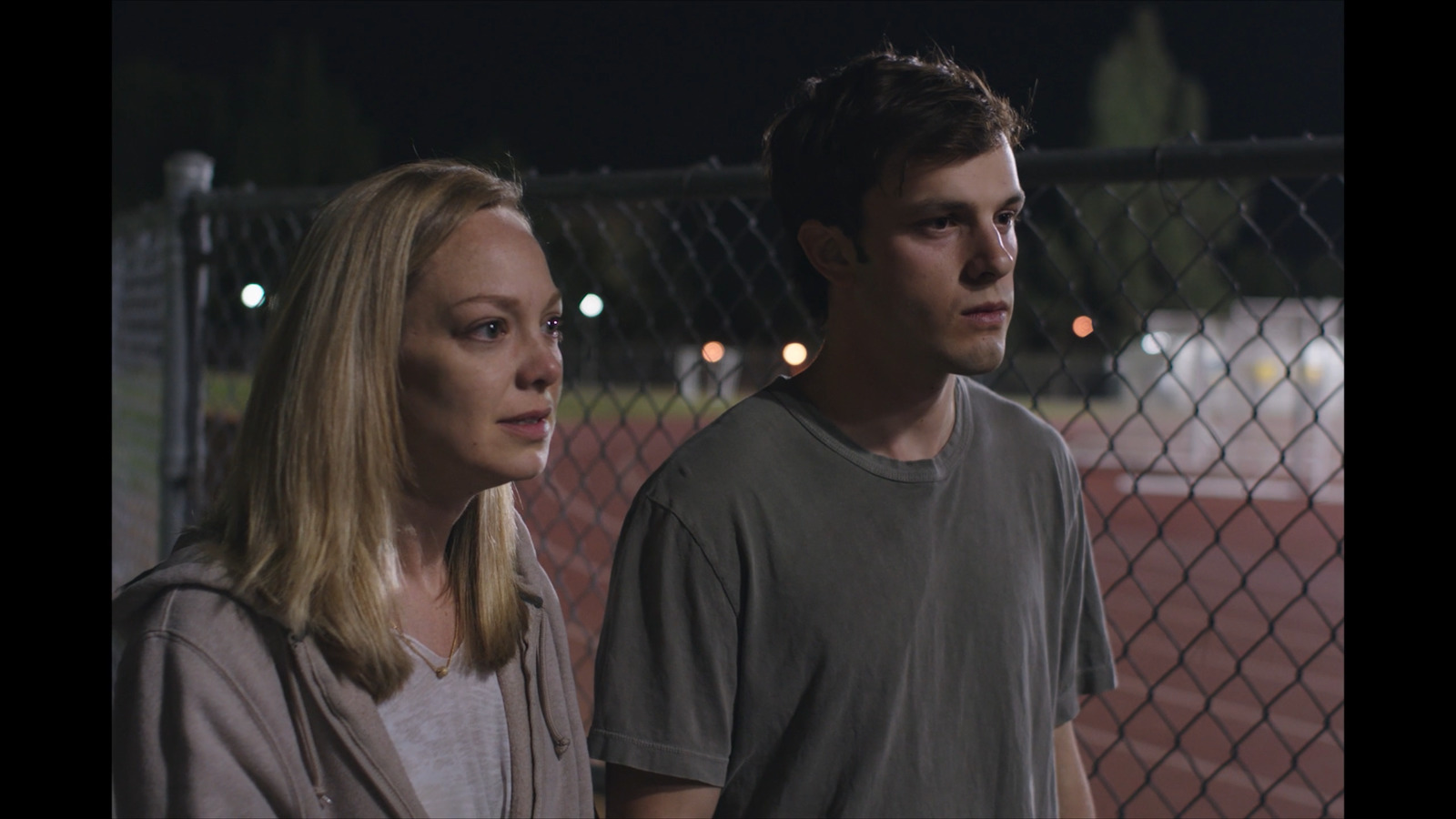 a man and a woman standing next to a fence