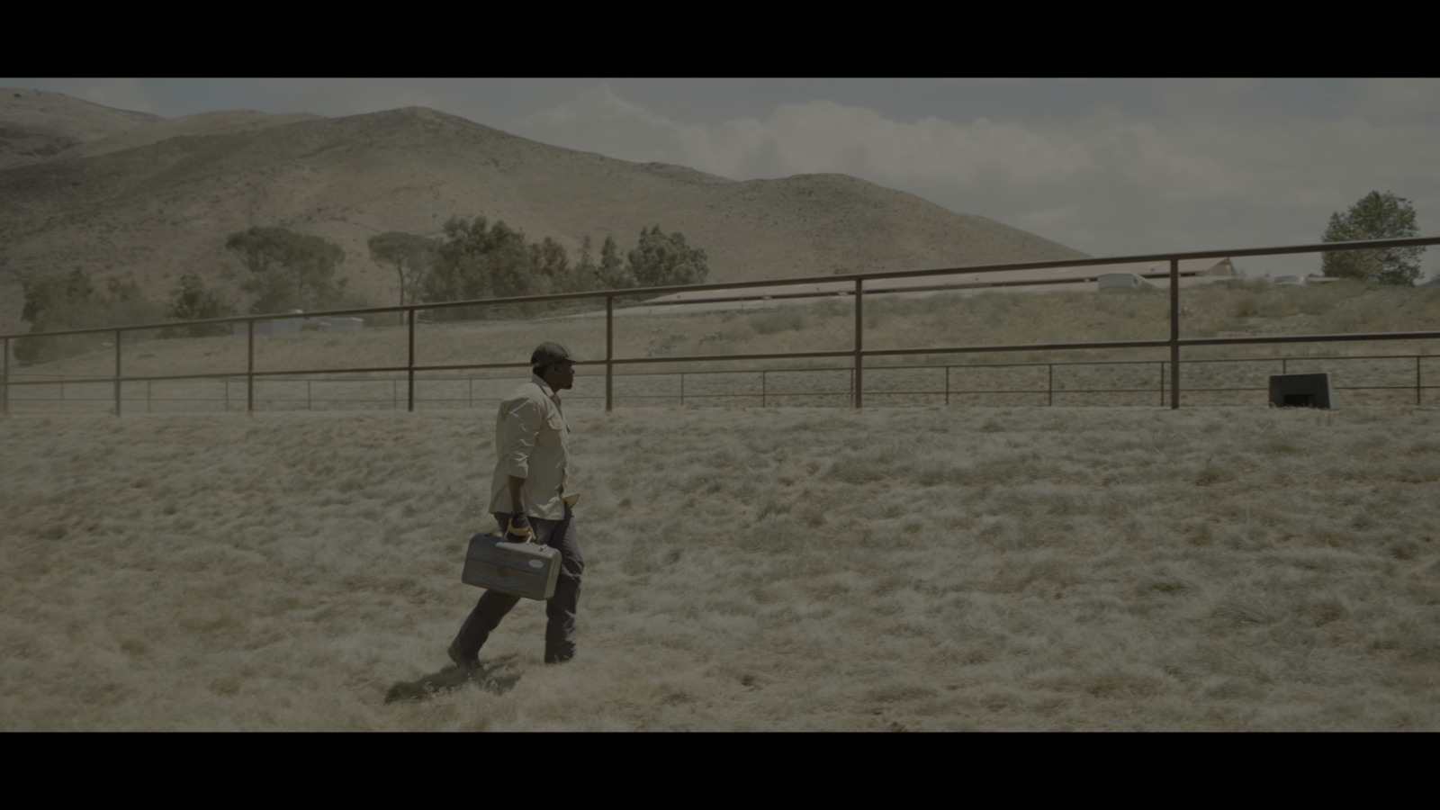 a man walking across a dry grass covered field