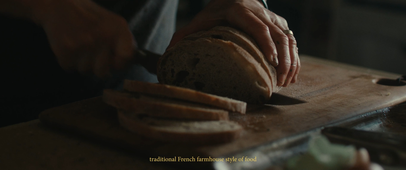 a person slicing a loaf of bread on a cutting board