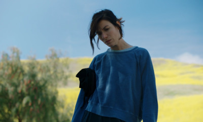 a woman standing in a field with a tree in the background