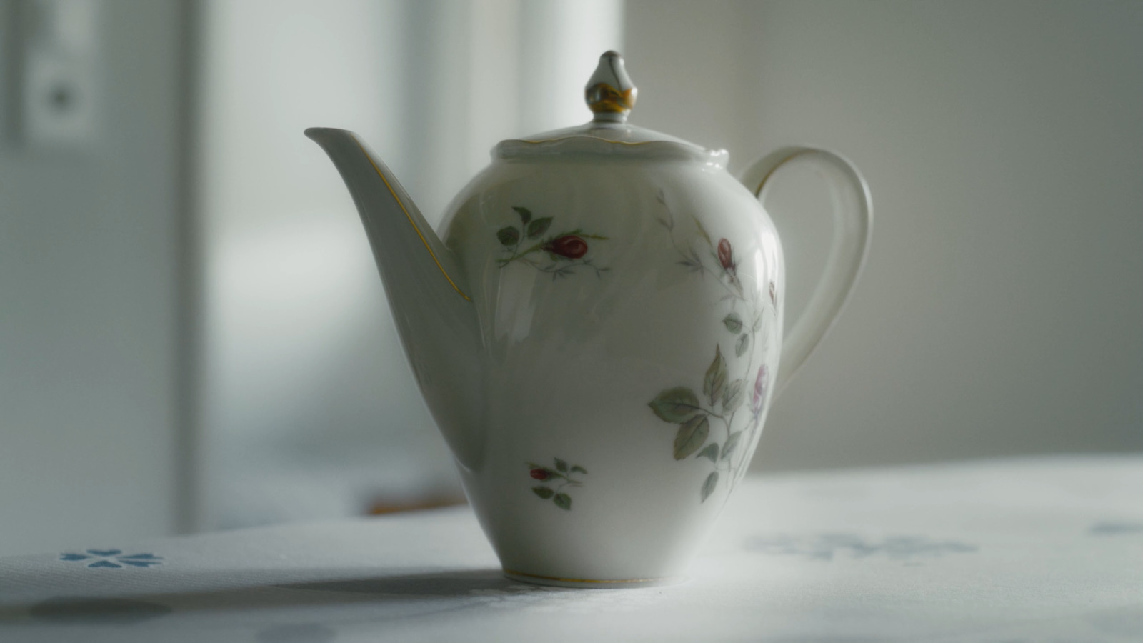 a white tea pot with a flowered design on it