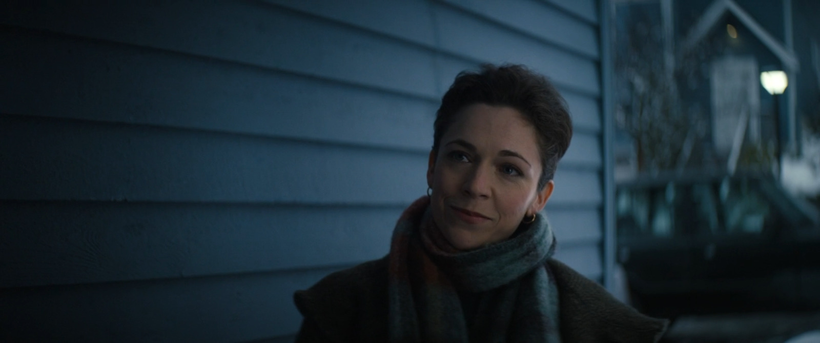 a woman standing outside of a house at night