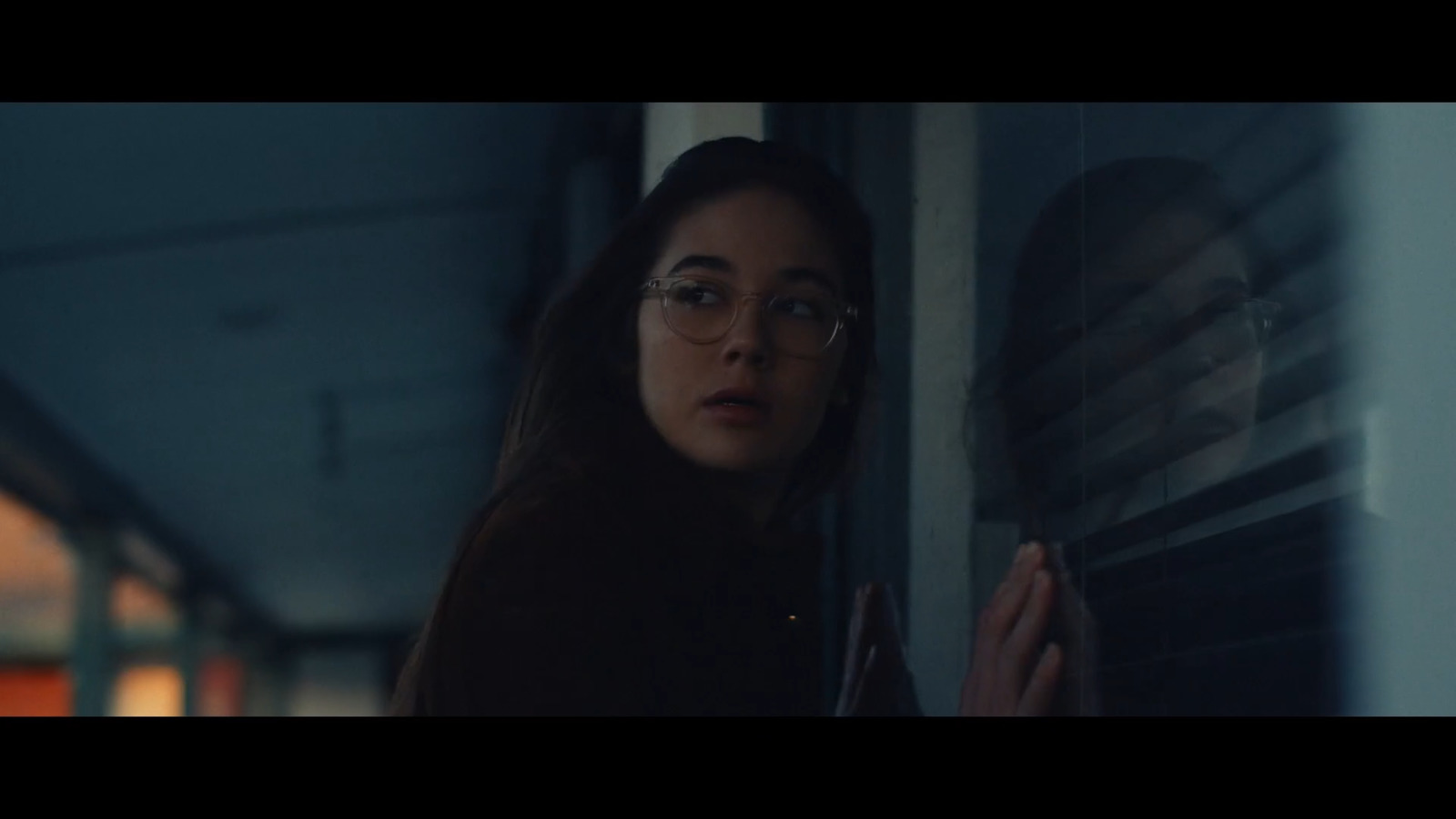 a woman wearing glasses looking out of a window