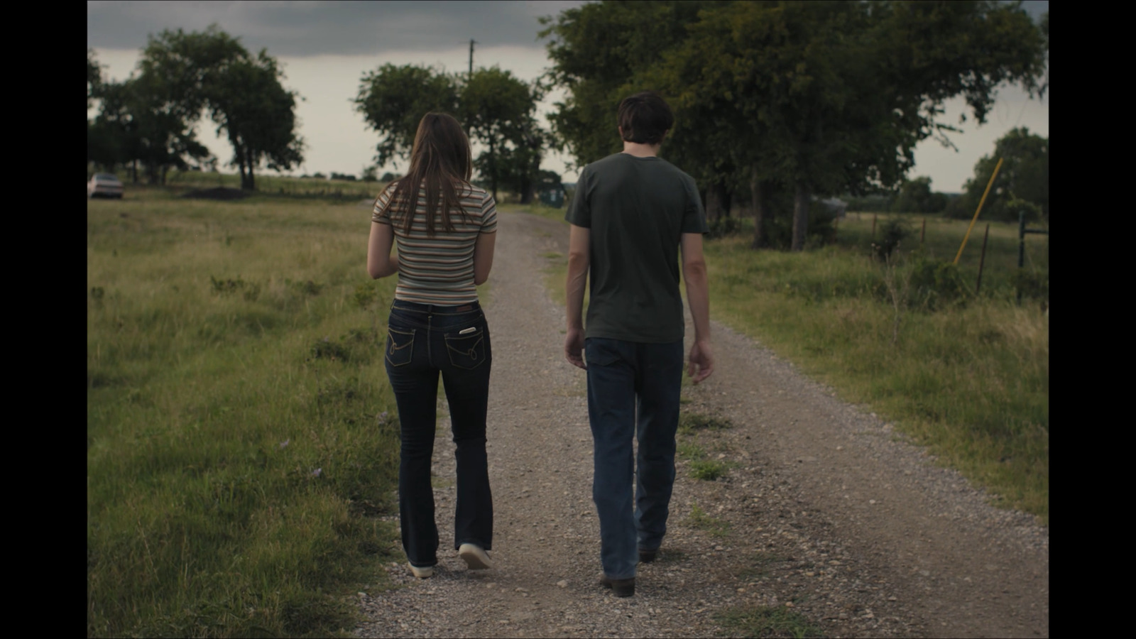 a man and a woman walking down a dirt road