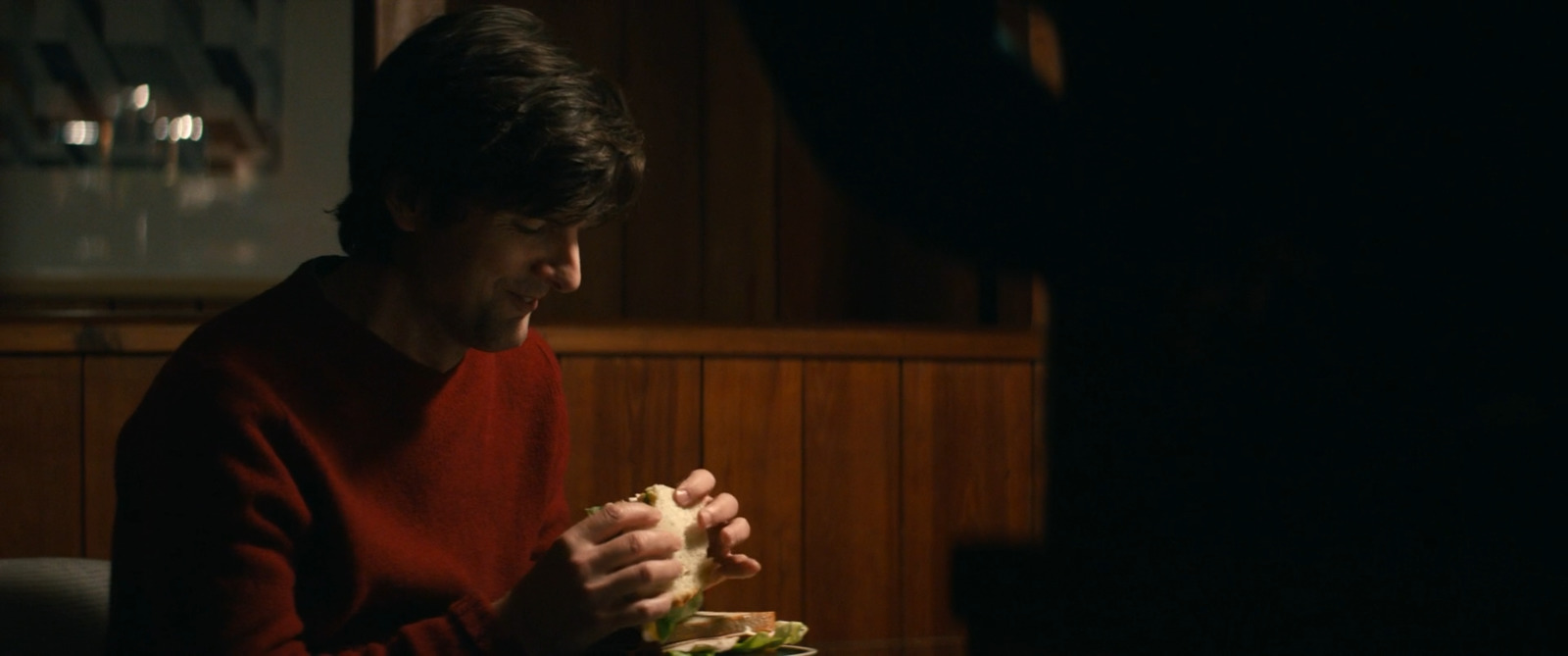 a man sitting at a table eating a sandwich