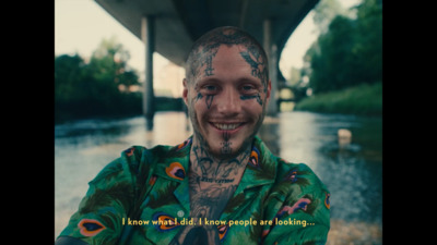 a man with tattoos on his face standing in front of a river