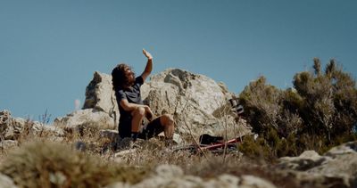 a man sitting on top of a rocky hillside