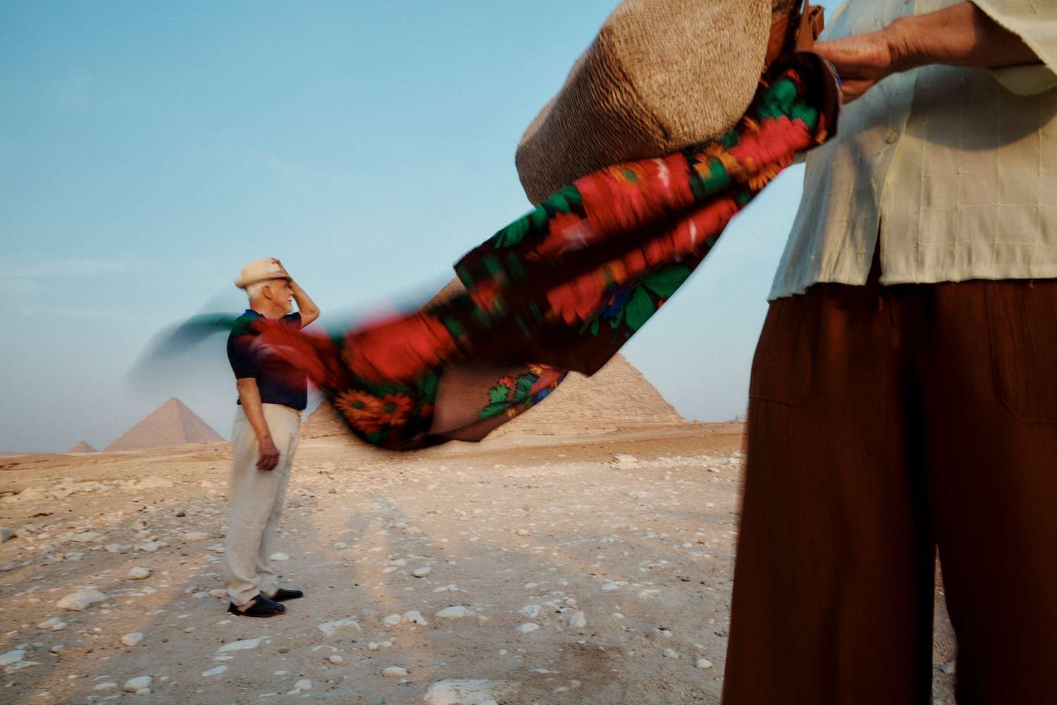 a man holding a large hat in front of a pyramid