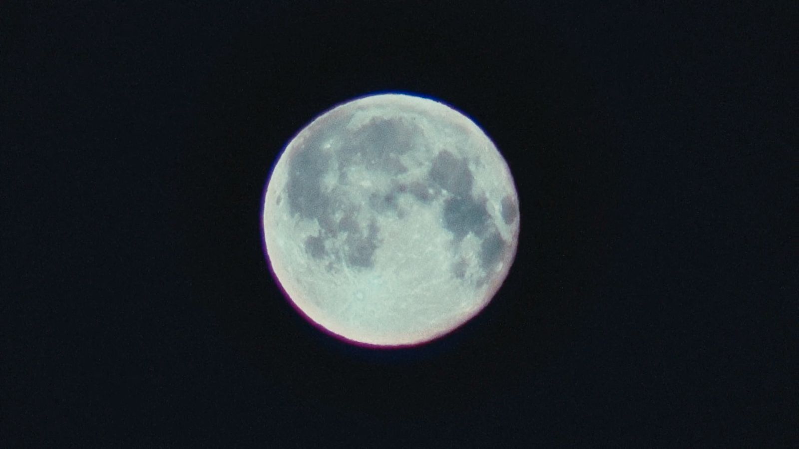 a full moon is seen in the dark sky