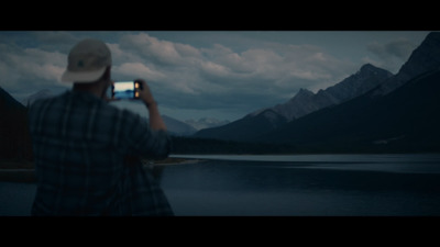 a man taking a picture of a mountain lake