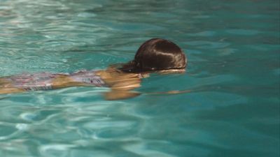 a woman swimming in a pool with a frisbee