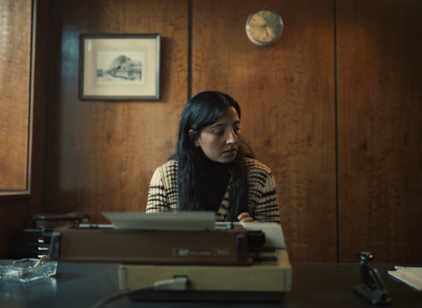 a woman sitting at a desk with a typewriter in front of her